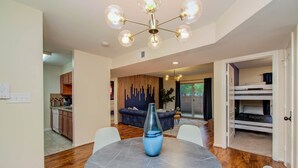 A modern interior with a dining area, kitchen, and a living space with a sofa and a decorative wall. - 3 Bedrooms, Spacious Central Condo w Pool (Houston)