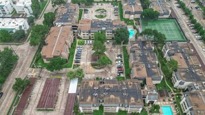 An aerial view of a residential area with multiple buildings, a tennis court, and a swimming pool. - 3 Bedrooms, Spacious Central Condo w Pool (Houston)
