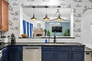 Una cocina moderna con lavavajillas integrado, un lavamanos con grifo y un salpicadero con diseño de azulejos.
