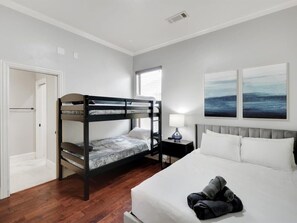 A bedroom with a bunk bed, a single bed, a bedside table with a lamp, and two wall-mounted paintings. - Luxury 4000sqft, Hot Tub, Games, Cinema, Ftworth, Attst (Kennedale)