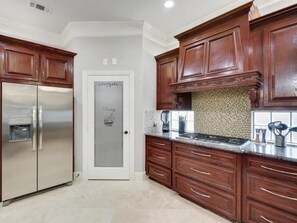 A kitchen with wooden cabinets, a stainless steel refrigerator, a tiled backsplash, and a door labeled 'Pantry.' - Luxury 4000sqft, Hot Tub, Games, Cinema, Ftworth, Attst (Kennedale)