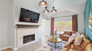 Una sala de estar con chimenea, sofá de cuero y televisión de pantalla plana.