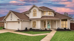 Ein zweistöckiges Haus mit Garage, Veranda und Auffahrt.
