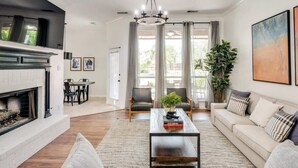 A spacious living room with a fireplace, a coffee table, and a sofa. - Southern Charm & Luxury Living - BBQ & Pool (Rockwall)
