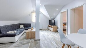 A modern loft apartment with a sectional sofa, a TV, a dining area, and a staircase leading to an upper level. - Gorgeous home in Gospic with sauna (Gospic)