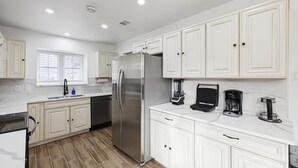 A modern kitchen with white cabinetry, a stainless steel refrigerator, a coffee maker, and a blender. - Best of Desoto 4br,3ba With Pool, Hottub, Cinema (DeSoto)
