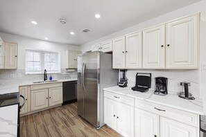A modern kitchen with white cabinetry, a stainless steel refrigerator, a coffee maker, and a blender. - Best of Desoto 4br,3ba With Pool, Hottub, Cinema (DeSoto)