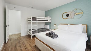 A bedroom with bunk beds, a bed with rolled towels, a wall clock, and a door to the left. - Best of Desoto 4br,3ba With Pool, Hottub, Cinema (DeSoto)