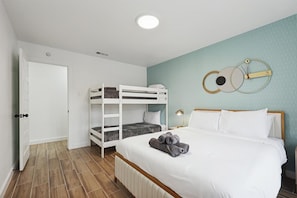 A bedroom with bunk beds, a bed with rolled towels, a wall clock, and a door to the left. - Best of Desoto 4br,3ba With Pool, Hottub, Cinema (DeSoto)
