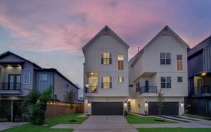 A two-story residential building with a garage, a front yard with a small tree, and a wooden fence. - Chic & Central 3BD Townhouse, Mins to DT & Midtown (Houston)