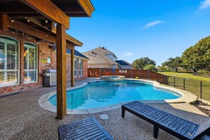 Ein Garten mit Swimmingpool, Sitzgelegenheit im Freien und einer Hollaube.