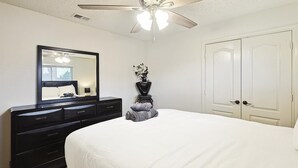 A bedroom with a bed, dresser, mirror, ceiling fan, and white doors. - Vista Valley Vacay, 5-bd w Pool & Cinema (Lewisville)