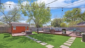 A backyard with a wooden shed, outdoor seating, a hot tub, and a barbecue area. - 4-bd Luxury Retreat Pool, Grill, Outdoor cinema (Richardson)