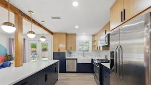 Una cocina moderna con electrodomésticos de acero inoxidable, armarios de madera e iluminación colgante.