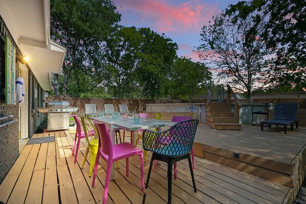 Eine Terrasse im Freien mit Tisch, Stühlen, einem Grill und einem Holzboden.