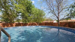 Una piscina con una cerca de madera y árboles al fondo.