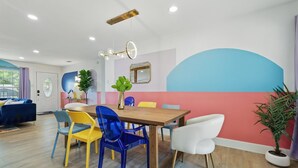 Un comedor con una mesa de madera, sillas coloridas y una lámpara en el techo.