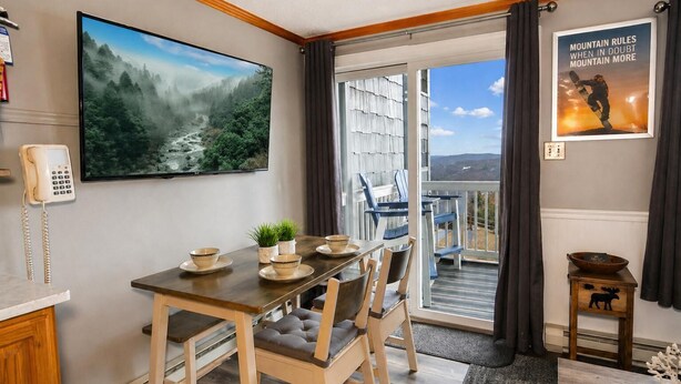 A dining area with a table set for four, a phone, a painting of a forest, and a poster on the wall. - ML 184:  Summer Mountain Side Escape - Wake up to Lovely Sunrises (Snowshoe)