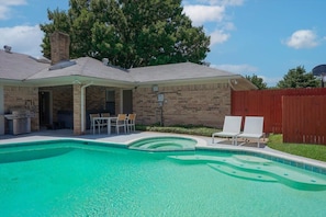 A backyard with a swimming pool, a barbecue area, and a covered patio with chairs. - Vibrant Spacious Home w/ Private Pool and Jacuzzi (Richardson)