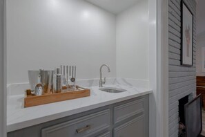 A bathroom with a white countertop, a sink, and a wooden tray with toiletries. - Vibrant Spacious Home w/ Private Pool and Jacuzzi (Richardson)