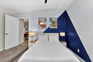 Habitación de hotel con una cama, dos lámparas de noche y dos obras de arte colgadas en la pared.