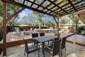 Un patio techado con piscina, mobiliario exterior y una terraza de madera.