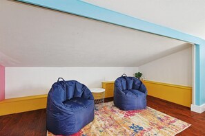 Ein Dachzimmer mit zwei blauen Sitzsäcken, einem kleinen runden Tisch und einem farbenfrohen Teppich.