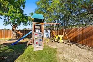 A backyard playground with a slide, climbing wall, and swings. - 5bd/2.5ba Luxury Modern Vibes Pool & Playground (Dallas)