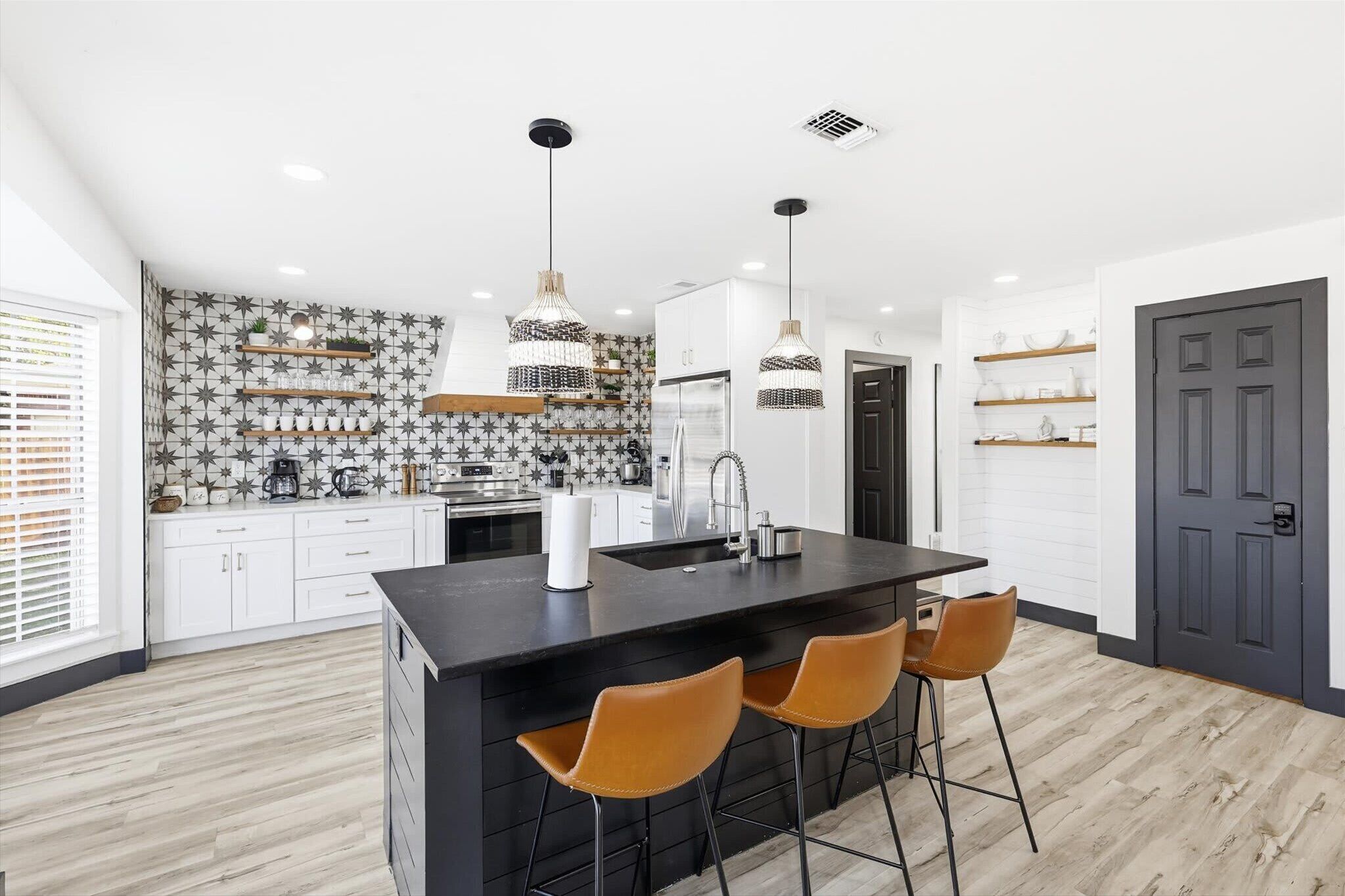 A modern kitchen with a central island, two pendant lights, and a backsplash with a star pattern.