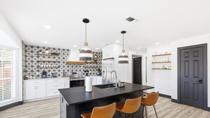 Une cuisine moderne dotée d’un îlot central, de deux suspensions et d’un revêtement mural orné d’un motif en étoile.