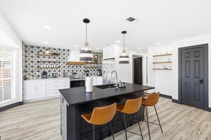 A modern kitchen with a central island, pendant lights, and a backsplash with a star pattern. - 5bd/2.5ba Luxury Modern Vibes Pool & Playground (Dallas)