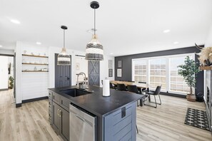 A modern kitchen with a central island, pendant lights, and a dining area with a table and chairs. - 5bd/2.5ba Luxury Modern Vibes Pool & Playground (Dallas)