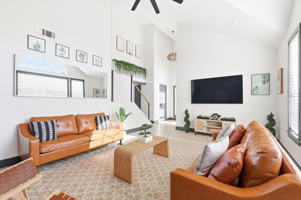 A spacious living room with a sofa, coffee table, and a staircase leading to an upper level. - 5bd/2.5ba Luxury Modern Vibes Pool & Playground (Dallas)