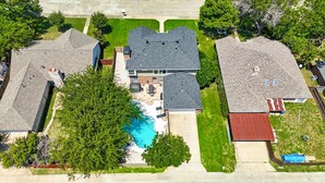 A residential area with three houses, a swimming pool, and a large tree. - Luxury 5BR Getaway w/ Pool, Hot Tub & cinema (DeSoto)