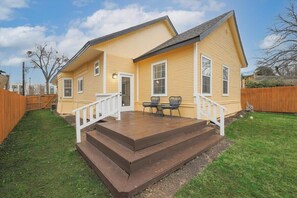 Ein zweistöckiges Haus mit Veranda, kleiner Terrasse und umzäunter Garten.