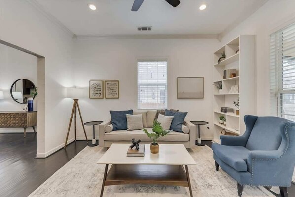 Un salon moderne comprenant un canapé, un fauteuil, une table basse et des objets décoratifs.