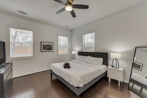 Ein Schlafzimmer mit Bett, Nachttischen, Deckenventilator und Fenstern.