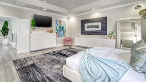 A spacious bedroom with a large bed, a flat-screen TV mounted on the wall, and a modern design. - Luxury Tropical Living - 4BR w Backyard Pool Oasis (Miami Lakes)