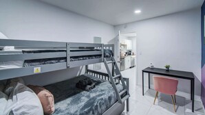 Ein kleines Zimmer mit Etagenbett, Schreibtisch und Stuhl.