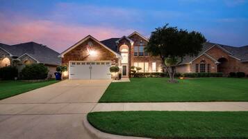 A two-story house with a garage, well-maintained lawn, and a driveway leading to the entrance.