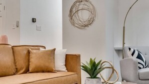 A modern living room with a beige sofa, a round coffee table, and a floor lamp. - Modern and Luxury DFW Mansion With Backyard Oasis (Fort Worth)