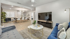 A spacious living room with a blue sofa, a marble coffee table, and a TV. - Luxury 4bed/2bath Hidden Gem w/ Backyard Oasis (North Richland Hills)