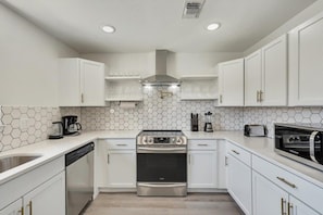A modern kitchen with white cabinetry, a stainless steel oven, and a hexagonal tile backsplash. - Luxury 4bed/2bath Hidden Gem w/ Backyard Oasis (North Richland Hills)