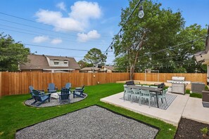 Ein Garten mit Grillplatz, Sitzgelegenheit im Freien und einem Holzzaun.