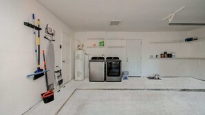 A laundry room with a water heater, two dryers, and cleaning supplies. - Stunning Modern Dream Home, 5-bd, Sleeps 14 (Houston)