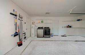 A laundry room with a water heater, two dryers, and cleaning supplies. - Stunning Modern Dream Home, 5-bd, Sleeps 14 (Houston)