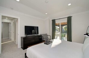 A bedroom with a bed, a TV, a dresser, and a balcony with a view. - Stunning Modern Dream Home, 5-bd, Sleeps 14 (Houston)