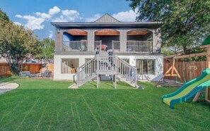 A two-story house with a balcony, a staircase, and a slide in the backyard. - Stunning Modern Dream Home, 5-bd, Sleeps 14 (Houston)