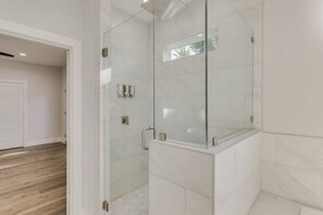 A modern bathroom with a glass shower enclosure, white tiled walls, and a wooden floor. - Modern and Comfortable Home Close to Downtown (Dallas)