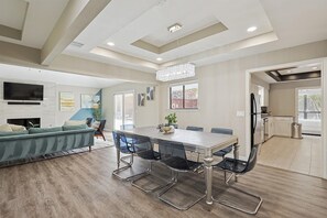 A modern living room with a dining area, a TV, and a fireplace. - Best of Allen at Fountain Park 5-bd/2-ba w/ Pool (Allen)
